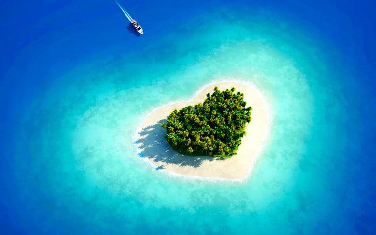 Île en forme de coeur au milieu d'eaux marines tropicales